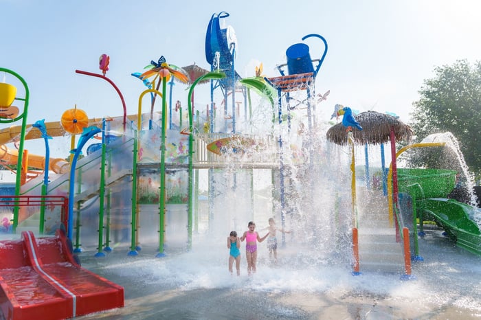 Children under splashing water at Bahama Beach Waterpark's Elevations aquatic play structure with colorful waterslides in Dallas, Texas