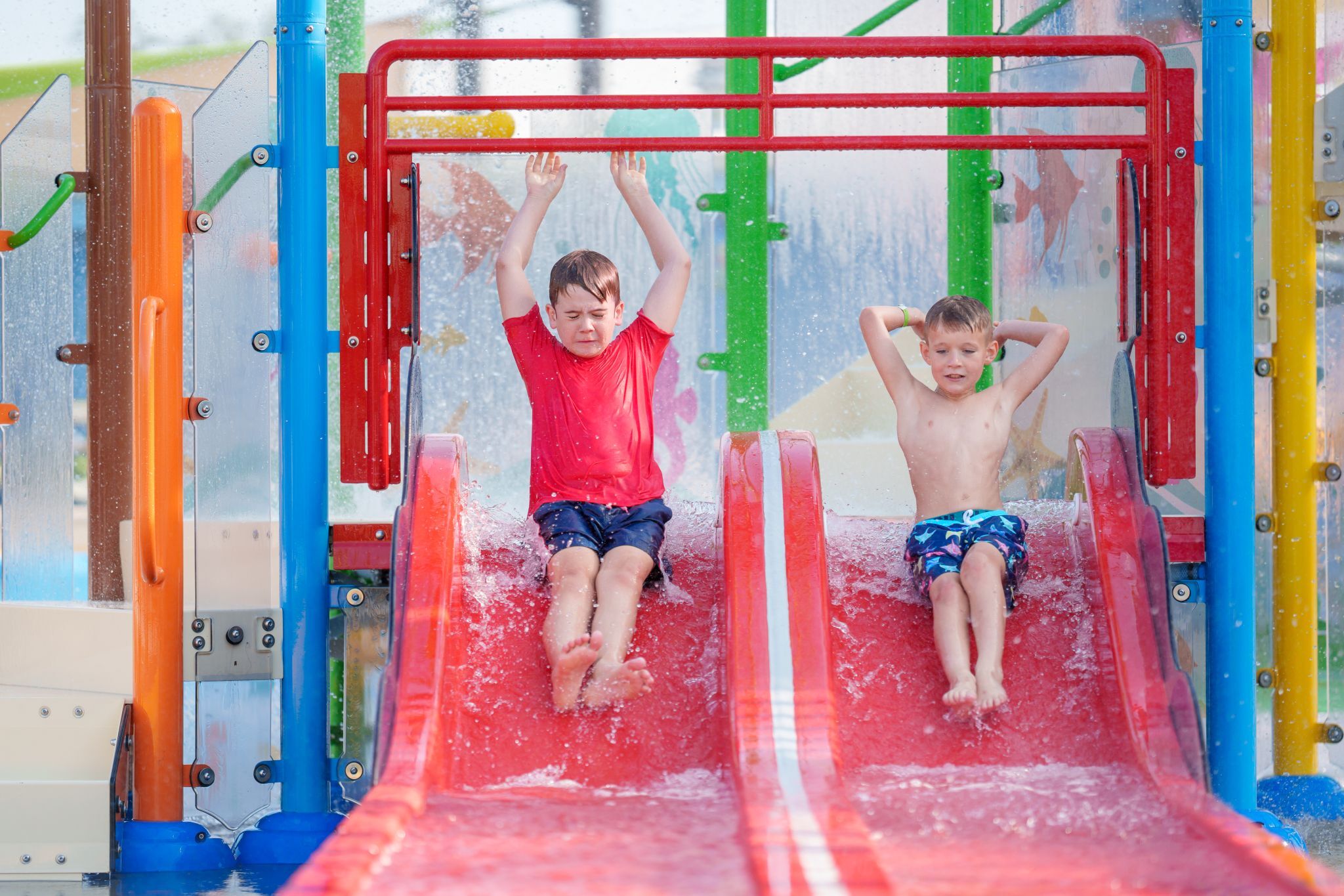 Children sliding down water slide on Bahama Beach Waterpark's Elevations aquatic play structure with colorful waterslides in Dallas, Texas