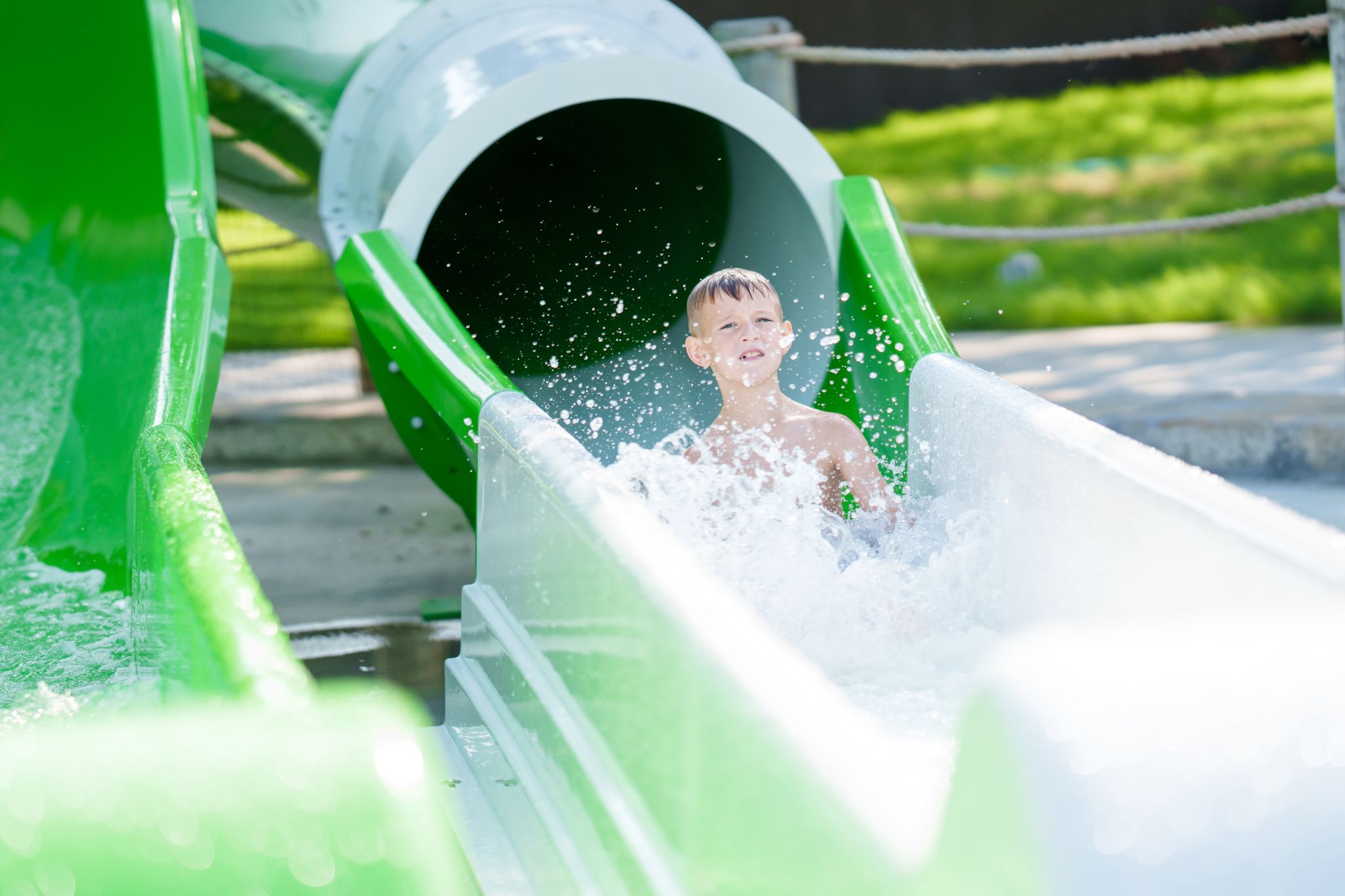 Child sliding down slide on Bahama Beach Waterpark's Elevations aquatic play structure with colorful waterslides in Dallas, Texas