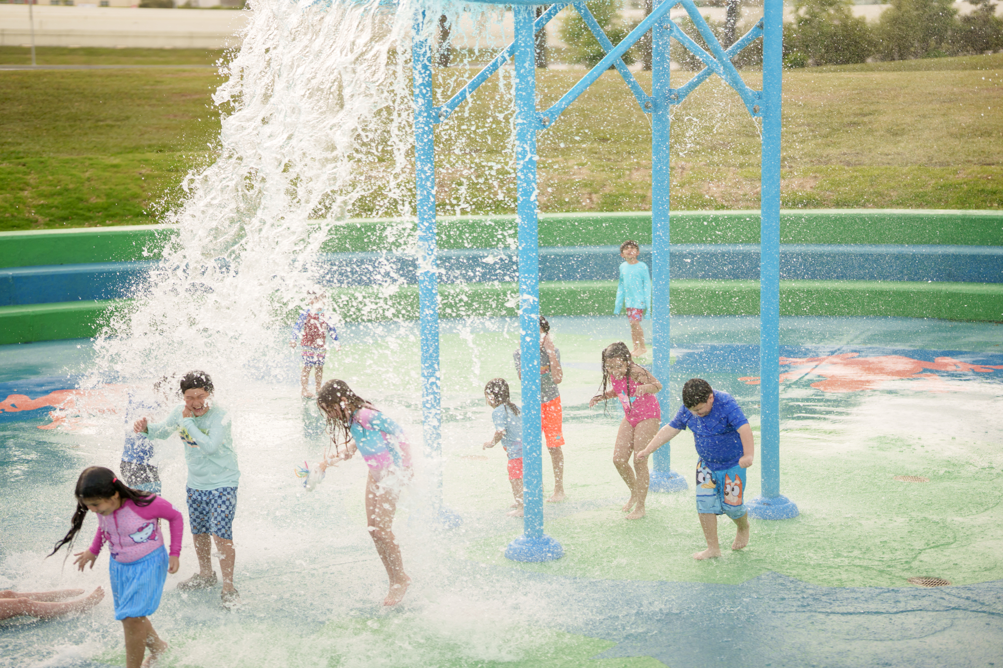 children playing under splash pad superwave dump bucket